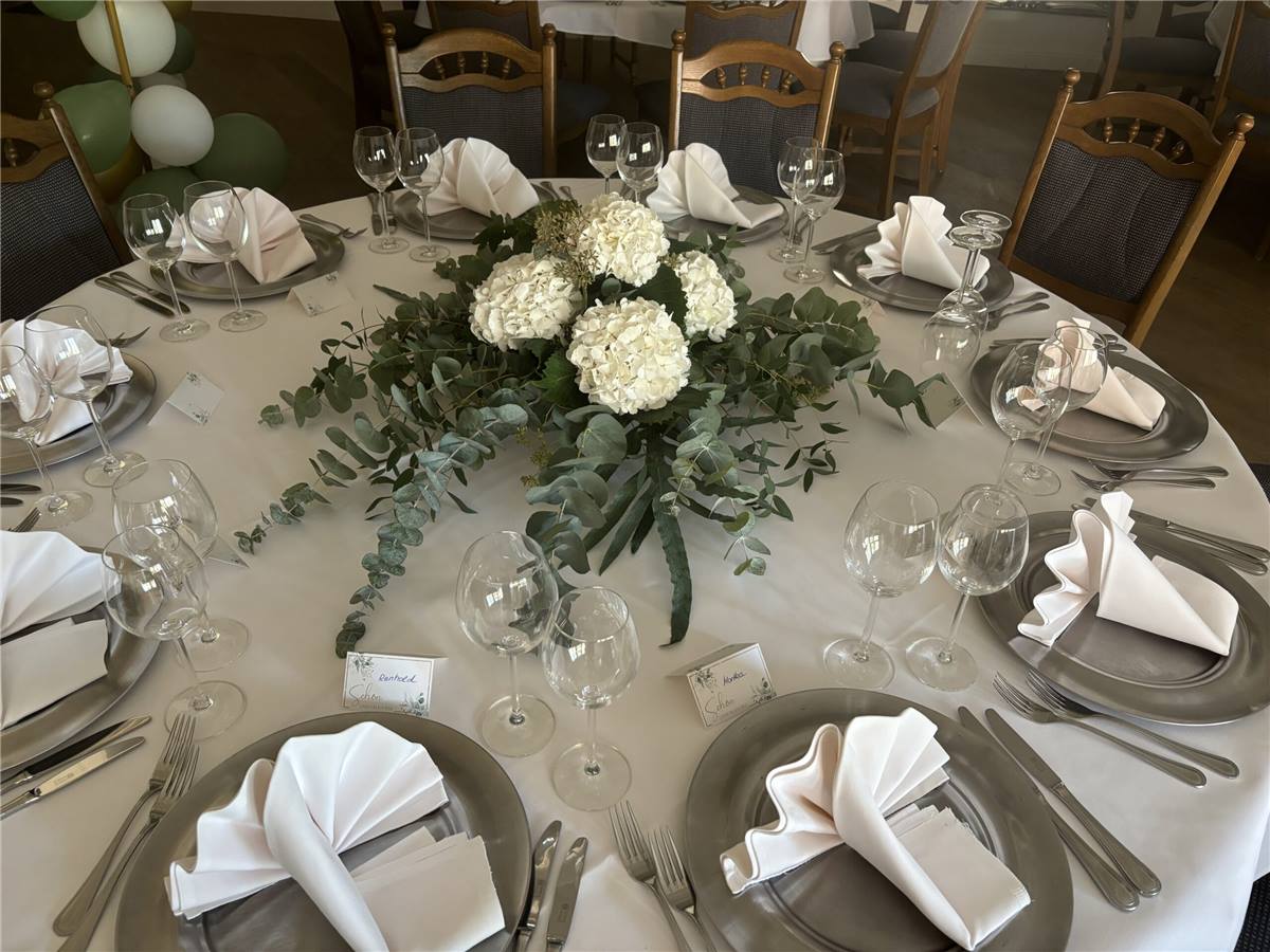 Festlich gedeckter runder Tisch mit weißem Blumengesteck